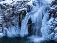 Bogenförmige Eissäule neben Wasserfall